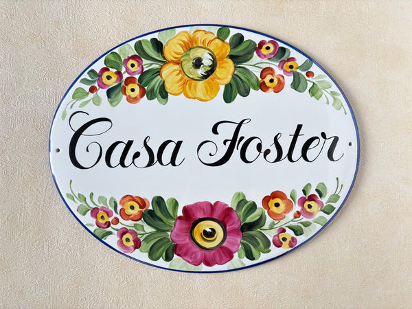 Oval ceramic house sign hand-painted with colored flowers and personalized with the name 'Casa Foster'