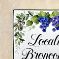 Decorative ceramic house sign hand-painted with grapes, leaves, and text on a textured beige background