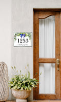 Ceramic house number tile hand-painted with grape and olives mounted on a concrete wall