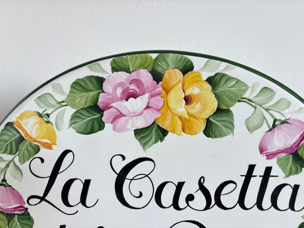 Detail of a ceramic house sign hand painted with pink and yellow roses