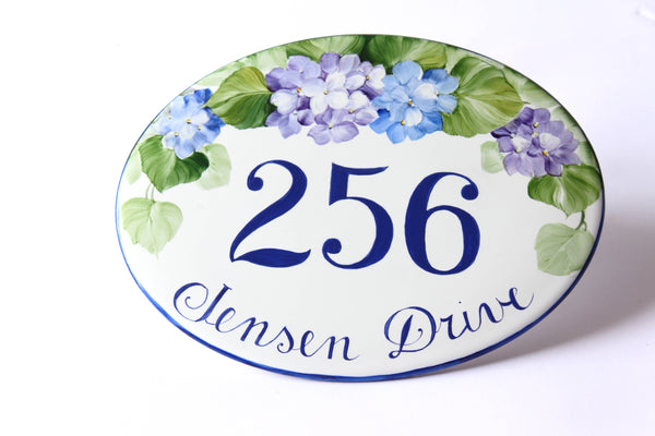 Oval-shaped address sign hand-painted with hydrangea design on a white background