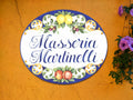 Ceramic House plaque hand-painted in Mediterranean style mounted on a orange wall