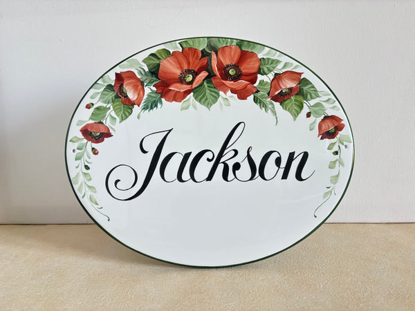 Oval ceramic family name sign hand-painted with red poppies and green leaves