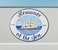 Oval ceramic house sign hand-painted with a ship in the sea, mounted on a wall