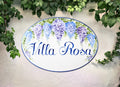 Oval porcelain house sign with hand-painted wisteria and the name "Villa Rosa" in blue script