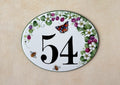 oval ceramic house number hand-painted with blackberries, white flowers, bees and a red butterfly