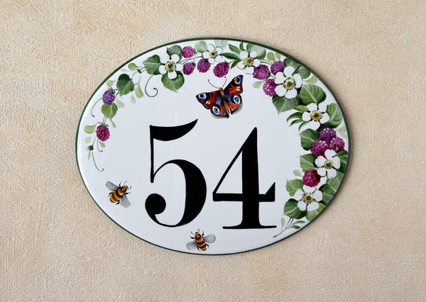 oval ceramic house number hand-painted with blackberries, white flowers, bees and a red butterfly