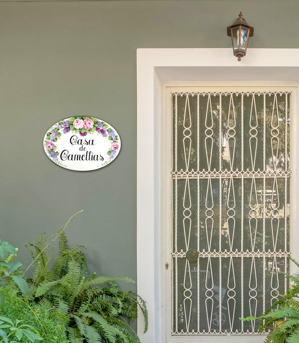 ceramic house sign hand painted with camellias mounted on a wall 
