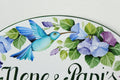 close-up details of an oval ceramic house sign hand painted with blue hummingbird and flowers