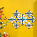 Colorful ceramic tiles hand-painted in Spanish style, arranged on yellow wall for garden, entryway, or poolside decoration.