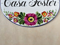 detail of pink and red flowers hand-painted on a ceramic house plaque
