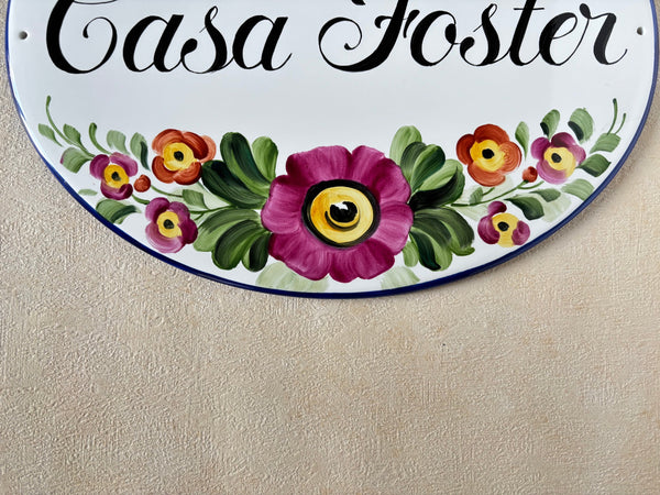 detail of pink and red flowers hand-painted on a ceramic house plaque