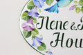 detail of a ceramic house plaque hand-painted with blue and purple flowers