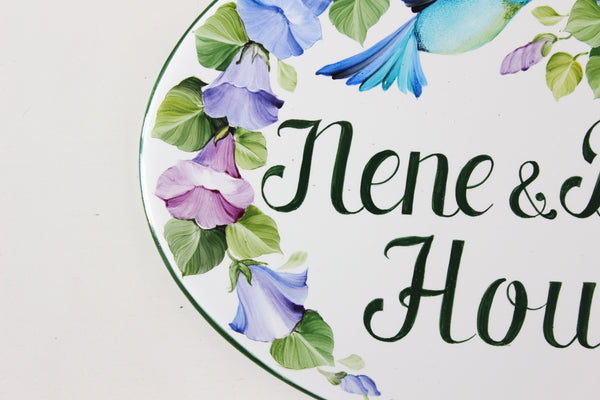 detail of a ceramic house plaque hand-painted with blue and purple flowers