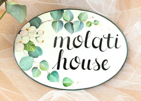 Oval ceramic family name house sign, hand painted with light green Eucalyptus leaves and white flowers