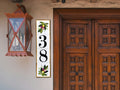 A vertical tile house number sign hand painted with olive branch at the top and bottom