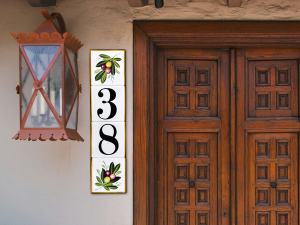 A vertical tile house number sign hand painted with olive branch at the top and bottom