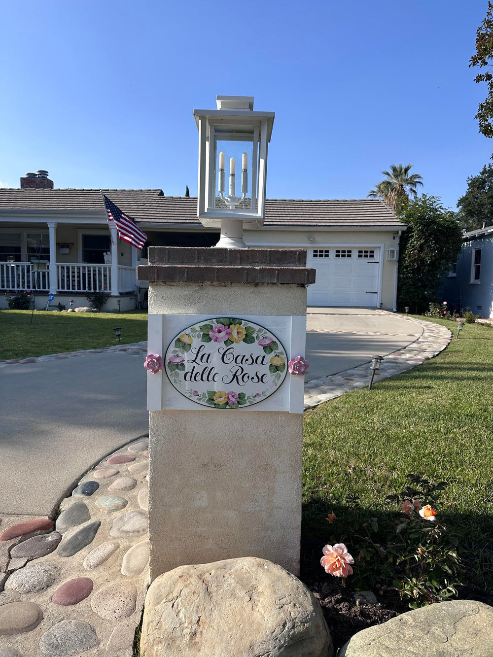 Ceramic house name sign hand painted with pink and yellow roses mounted on a pillar