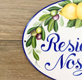 close-up detail of a ceramic house sign hand painted with lemons, olive, leaves and blue border