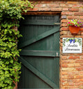 house name tile hand-painted with grapes and olives mounted on a brick wall