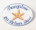 ceramic beach house sign hand painted with yellow starfish in mosaic style; then name is painted in blue on top and the address is on the bottom