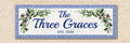 A rectangular decorative wall sign hand painted with a blue Greek key border and watercolor olive branches with  'The Three Graces' and 'EST. 2026' in blue script, shown against a beige textured wall.