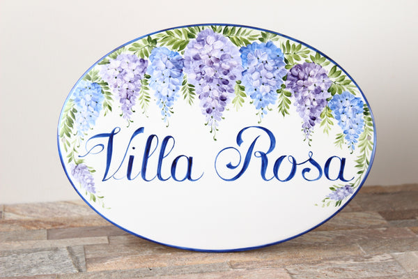Ceramic oval house plaque hand painted with blue and purple wisteria flowers, personalized with the name painted in blue