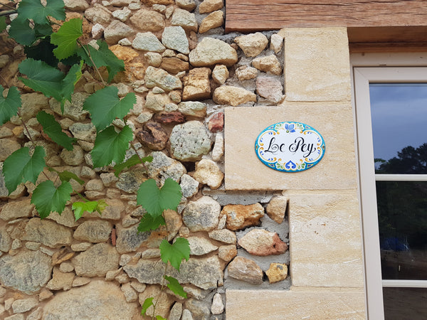 ceramic house name sign mounted on a stne wall