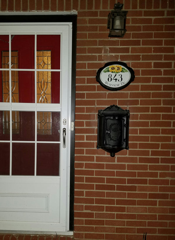 ceramic address plaque with sunflowers mounted on a brick wall